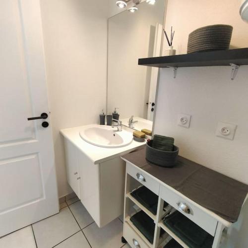 La salle de bains blanche est pourvue d'un lavabo et d'un miroir. dans l'établissement Spacieux studio dans résidence avec parking privé, à Clermont-Ferrand
