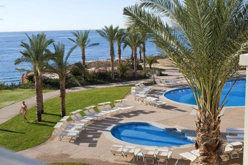 a resort with a pool and chairs and the ocean at Stella Di Mare Beach Hotel & Spa in Sharm El Sheikh