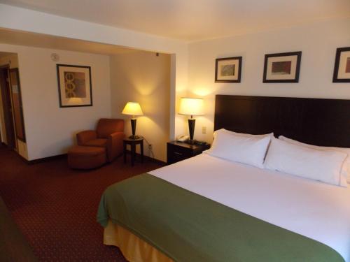 a hotel room with a large bed and a chair at Holiday Inn Express Syracuse-Fairgrounds, an IHG Hotel in Warners