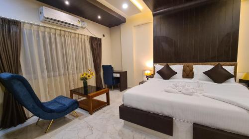a hotel room with a bed and a blue chair at Hotel EDEN in Kārwār