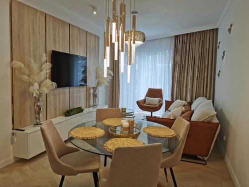 un salon avec une table, des chaises et une télévision dans l'établissement Gold Apartment B33 Let's Sea Baltic Park Gąski, à Gąski