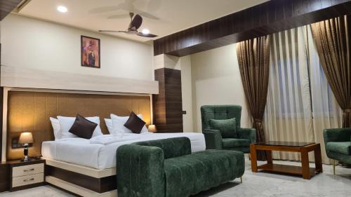 ein Schlafzimmer mit einem Bett und zwei grünen Stühlen in der Unterkunft Hotel EDEN in Kārwār