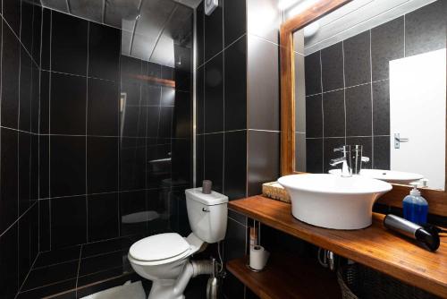 a bathroom with a toilet and a sink and a mirror at Modern 2 bedroom apartment in vibrant Melville 99 in Johannesburg