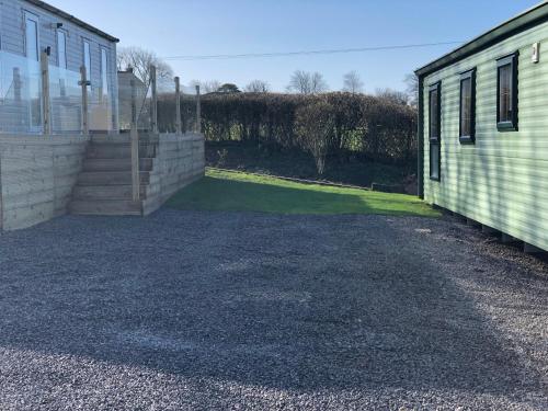 a gravel driveway next to a building and a yard at Delightful 2-bed static set in a peaceful village in Gilcrux