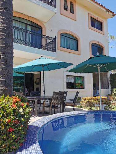 a house with a swimming pool with two umbrellas at Delfin in Cruz de Huanacaxtle