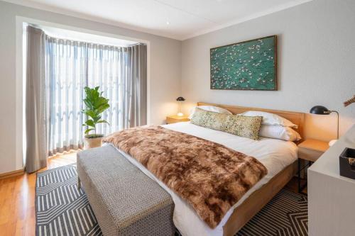 um quarto com uma cama grande e uma janela grande em Modern apartment in culturally vibrant Melville 22 em Joanesburgo