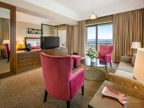 a living room with pink chairs and a television at Hotel Çelik Palas Convention Center & Thermal SPA in Bursa