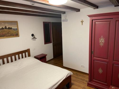 a bedroom with a bed and a red door at Dorul Pescarului in Curtea de Argeş