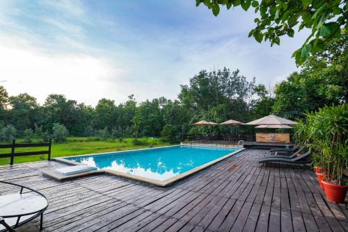 a swimming pool on a patio with a wooden deck at LA SELVA Resort, Pench National Park in Khawāsa
