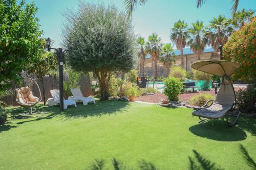 a yard with a lawn with a chair and a umbrella at Suites in the Galilee in Qiryat Shemona