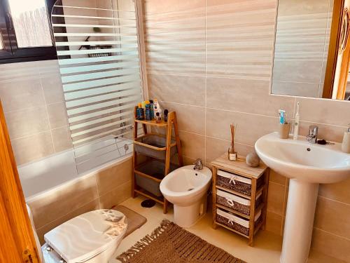 a bathroom with a sink and a toilet and a tub at Stillvolle Villa mit Terrasse, Garten und Grill in Lajares