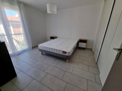 ein Schlafzimmer mit einem Bett auf einem Fliesenboden in der Unterkunft Maison - proche centre ville in Céret