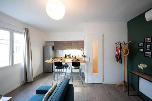un salon avec un canapé bleu et une cuisine dans l'établissement Appartement centre village, clim et parking gratuit, à Aigues-Mortes