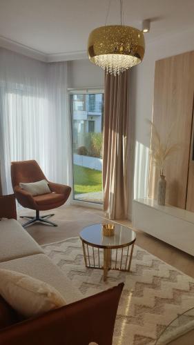 a living room with a couch and a table and a chair at Gold Apartment B28 Let's Sea Baltic Park Gąski in Gąski