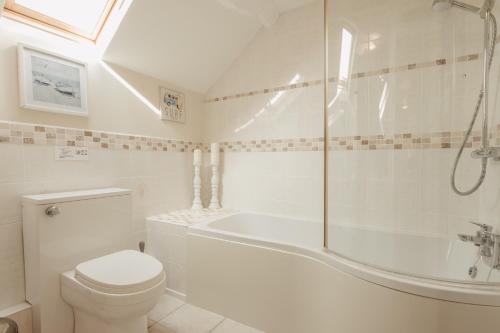 ein Badezimmer mit Badewanne, Toilette und Dusche in der Unterkunft Bennar Isa Cottages Dyffryn Ardudwy in Barmouth