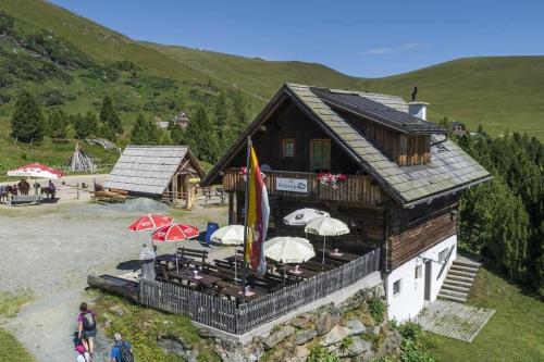 a building with a deck with umbrellas on it at Zirbenhütte am Falkert auf der Heidi-Alm in Koflach