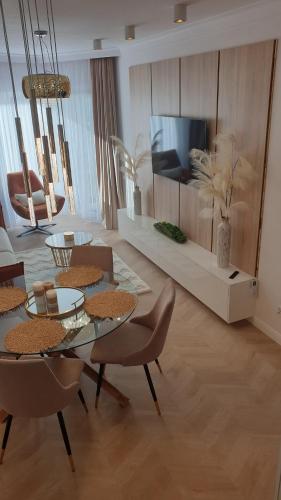 un salon avec une table, des chaises et une télévision dans l'établissement Gold Apartment B28 Let's Sea Baltic Park Gąski, à Gąski