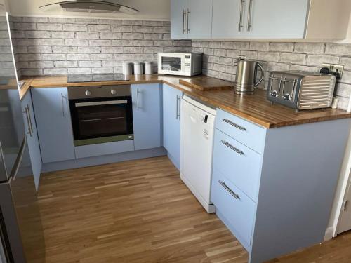 a kitchen with white cabinets and a wooden floor at Stylish & Spacious 2 Storey, 3 Bed Apartment in Kent