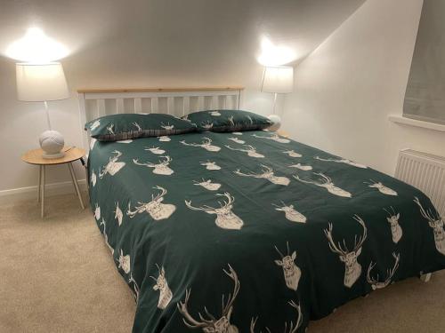 a bed with a green blanket with deer on it at Stylish & Spacious 2 Storey, 3 Bed Apartment in Kent