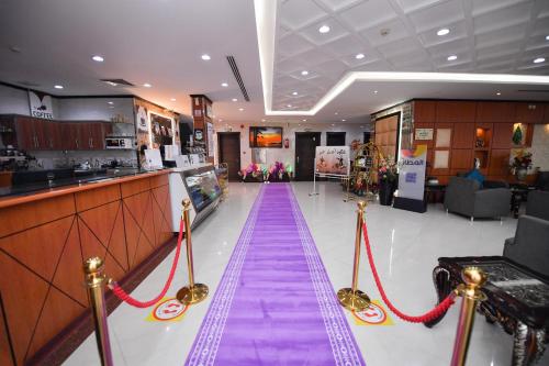 un largo pasillo púrpura en una tienda con cuerdas rojas en Aseel Alsharq Hotel en Riad