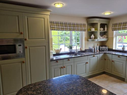 eine Küche mit weißen Schränken und einer Mikrowelle in der Unterkunft Hillview House in Bellaghy