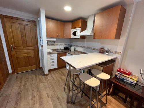 a kitchen with wooden cabinets and a table and stools at Precioso apartamento en San Isidro , ski , snow in San Isidro