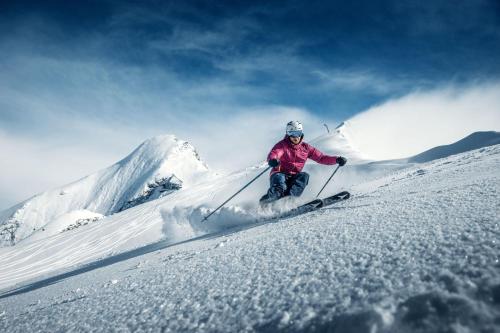 a person is skiing down a snow covered slope at Aurora Mountain Chalet by we rent, SUMMERCARD INCLUDED in Kaprun