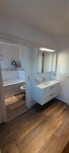 a white bathroom with a sink and a tub at Ferienwohnung Alter Kräuterhof in Mildenau