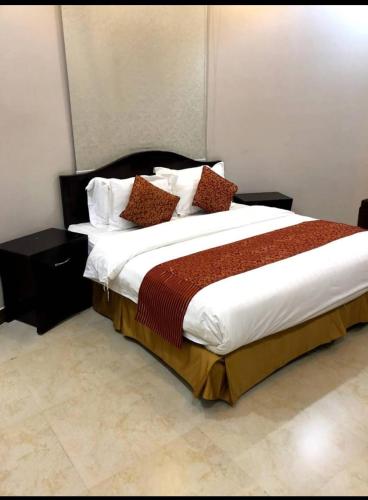 - une chambre dotée d'un grand lit avec des draps et des oreillers blancs dans l'établissement فيو بلس للشقق الفندقية, à Khamis Mushait