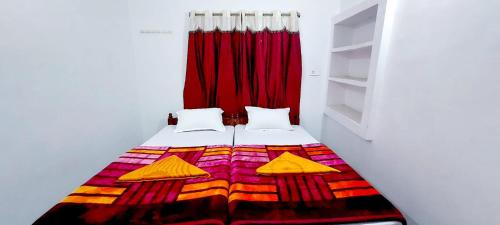 a bedroom with a bed with a red curtain at Nilam Guest House in Bodh Gaya