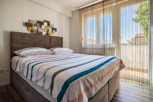 a bedroom with a large bed and large windows at Apartments Nina in Zadar