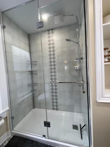 a shower with a glass door in a bathroom at Comfortable and Convenient Apartment in Central Niagara in St. Catharines