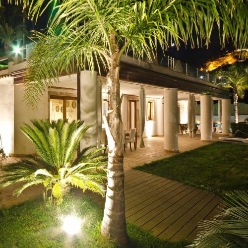 a palm tree in front of a house at night at Villa Zagara Garden Spectacular Sea View in Taormina in Taormina