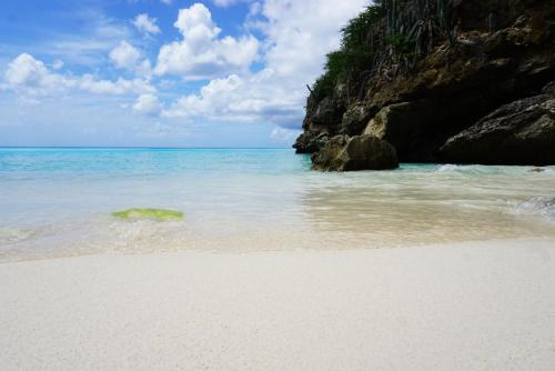 a sandy beach with the ocean and rocks at Boca Simon Vacation Curacao in Willemstad