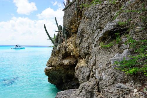 a boat in the water next to a rocky cliff at Boca Simon Vacation Curacao in Willemstad
