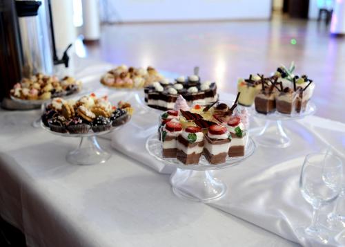 a table with several different cakes and desserts on plates at Hotel Galicja in Ulanów