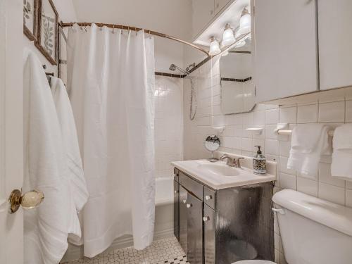 Baño blanco con cortina de ducha y lavamanos en The Charming Pecan Place! en Oklahoma City