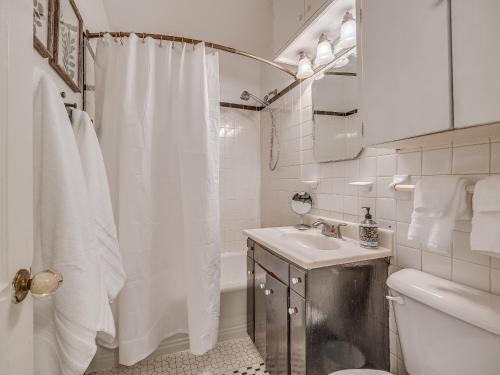 a white bathroom with a shower curtain and a sink at The Charming Pecan Place! in Oklahoma City