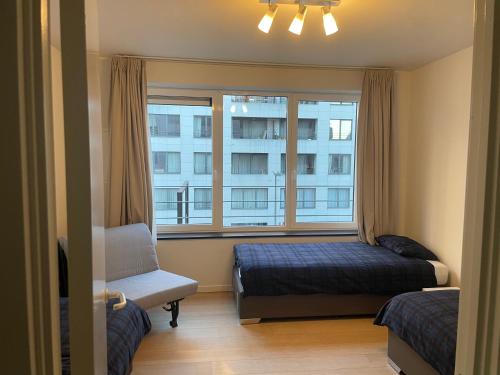 a bedroom with a bed and a window and a chair at Apartment in Heart of Brussel City with Balcony View in Brussels