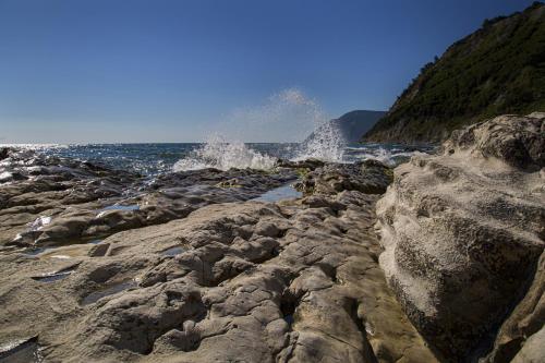 a rocky beach with waves crashing on the shore at BREZZA DEL CONERO in Ancona