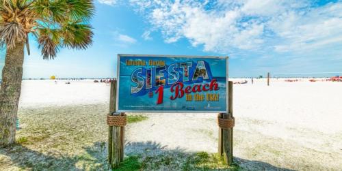 a sign on the beach next to a palm tree at Spacious 5BR Private Home, Private Pool & Salt Water Spa, Minutes from Beaches in Bradenton