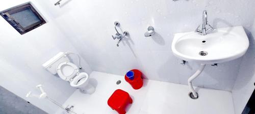 a white bathroom with a sink and a toilet at Nilam Guest House in Bodh Gaya