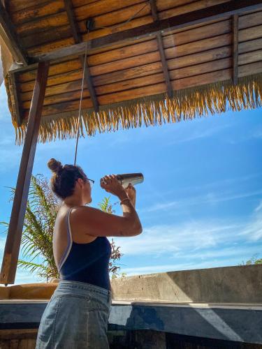 a woman standing under a thatched roof holding a object at Hotel Vista de Olas in Santa Teresa Beach