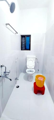 a white bathroom with a toilet and a sink at Nilam Guest House in Bodh Gaya