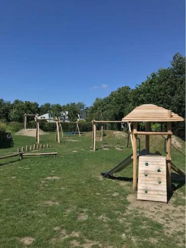a wooden playground with a gazebo in a field at HÜBSCHES FERIENHAUS IN OUDDORP - fußläufig zum Strand und Zentrum in Ouddorp