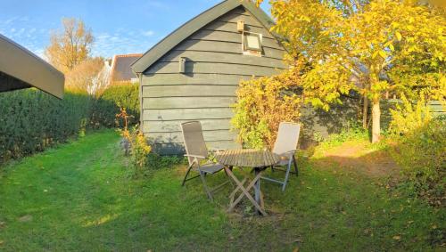 a table and chairs in front of a shed at Het Duinhuisje in Goedereede