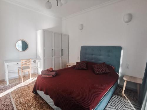Schlafzimmer mit einem Bett mit einer roten Decke und einem Schreibtisch in der Unterkunft RODIES apartment in Chalkida