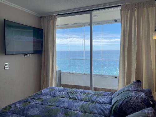a bedroom with a bed and a large window with the ocean at Una vista increíble al Pacifico in Concón