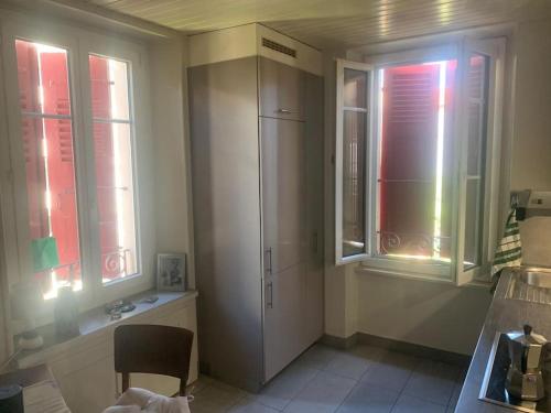 a kitchen with a refrigerator and two windows at A deux pas du lac Leman ( Ouchy) joli appartement in Lausanne