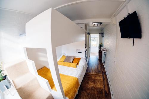 a small room with a bed with yellow sheets at Bijou Annexe, Sea View, Private Entrance & Parking - FOLKESTONE in Folkestone